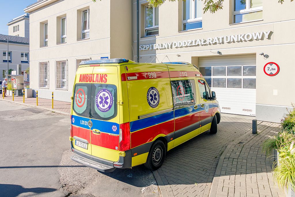 Wjazd na SOR SPSK Nr 4 w Lublinie. Przed budynkiem stoi karetka pogotowia.