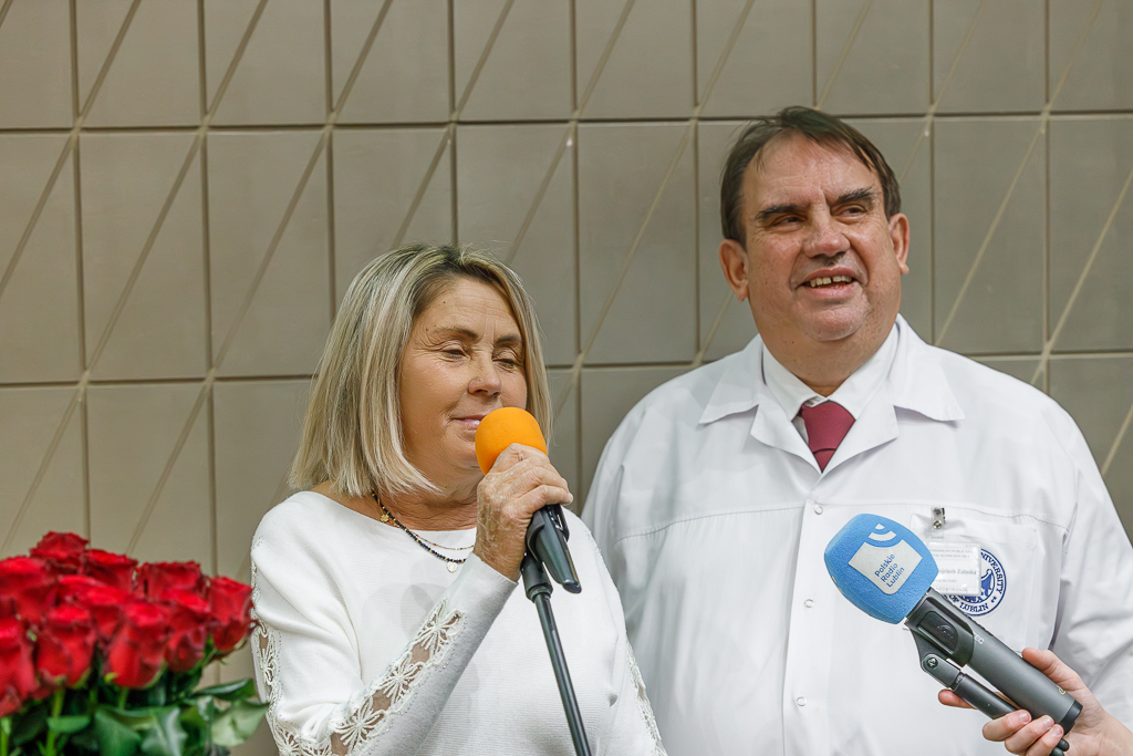 Pacjentka Klinicznego Oddziału Sztucznej Nerki, pani Małgorzata i rektor Uniwersytetu Medycznego w Lublinie i lekarz kierujący Kliniką Nefrologii SPSK Nr 4 w Lublinie prof. dr hab.n.med. Wojciech Załuska przed dwoma mikrofonami. Obok róże.