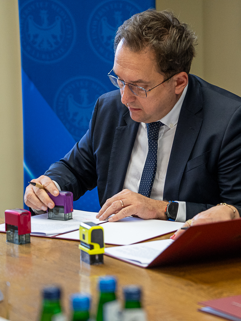 Dyrektor Naczelny USK Nr 4 w Lublinie Michał Szabelski podpisuje porozumienie o współpracy. W prawej ręce trzyma pieczątkę i długopis. Obok leżą pieczątki innych sygnatariuszy porozumienia.