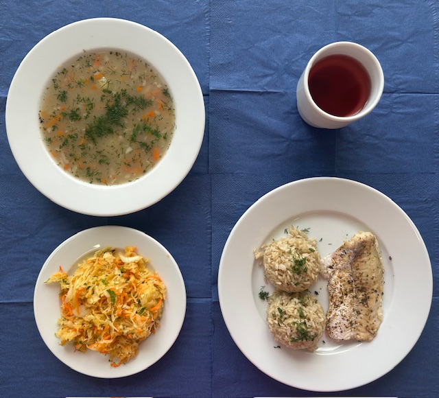 na talerzach krupnik jęczmienny, ryba pieczona, ryz brązowy, surówka z kiszonej kapusty, w kubku kompot