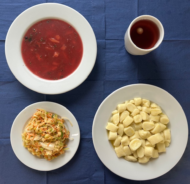 na talerzach barszcz czerwony, kluski leniwe, surówka z pora i jabłka w kubku kompot